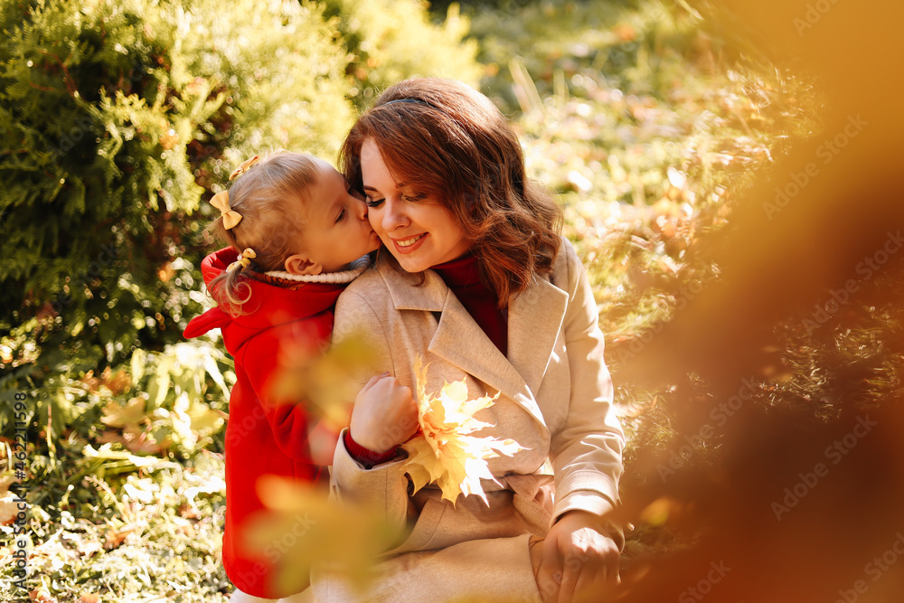 Autumn landscape. Happy mom and daughter, a child in a coat hugging together, walking and having fun in the fall forest on Mother's Day in nature outdoor. Selective focus Autumn landscape. Happy mom and daughter, a child in a coat hugging together, walking and having fun in the fall forest on Mother's Day in nature outdoor. Selective focus