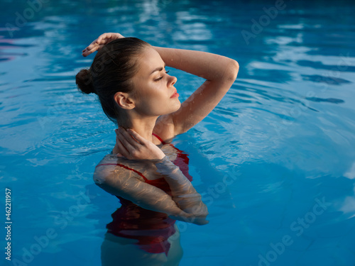 attractive woman in red swimsuit swims in clear pool water cropped view