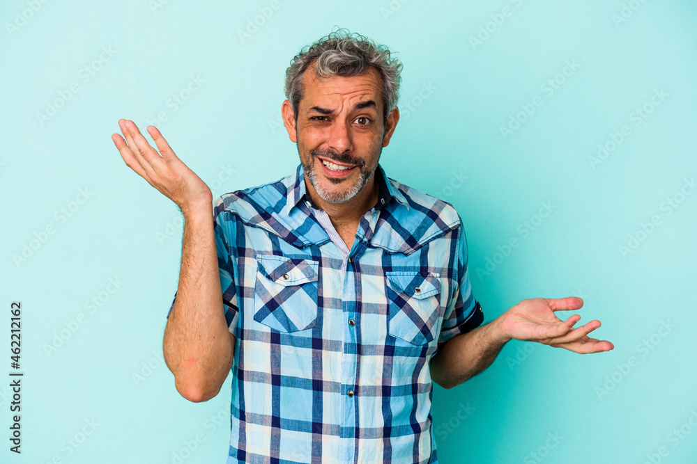 Middle age caucasian man isolated on blue background confused and doubtful shrugging shoulders to hold a copy space. Middle age caucasian man isolated on blue background confused and doubtful shrugging shoulders to hold a copy space.