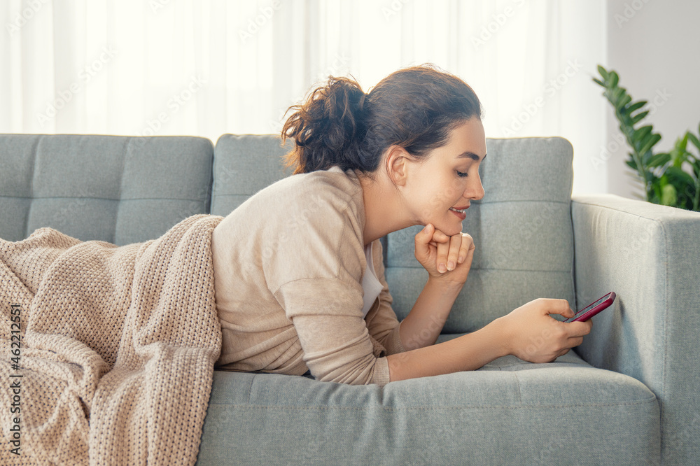 woman is using a phone sitting on a sofa woman is using a phone sitting on a sofa