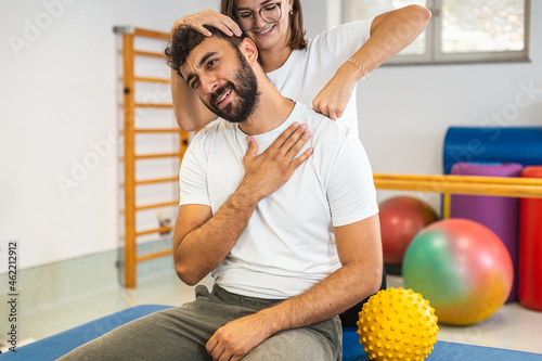 Woman Physical Therapist Stretching the Injured Neck of a Male Patient.