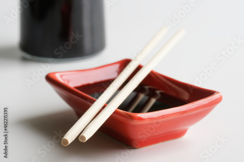 Rectangular Japanese sauce bowl - seyuzaru, chopsticks - varibashi and a bottle of soy sauce on a light background