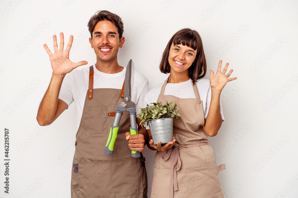 Young mixed race gardener couple isolated on white background smiling cheerful showing number five with fingers. Young mixed race gardener couple isolated on white background smiling cheerful showing number five with fingers.