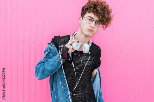 Young gay man wearing eyeglasses in front of pink wall photo