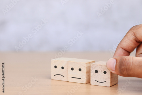 Hand holding wooden cube with smiley face icon, Customer Service Satisfaction Concept