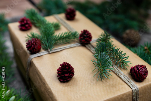 Gift box and decoration .Christmas tree branches and pine cones wooden background