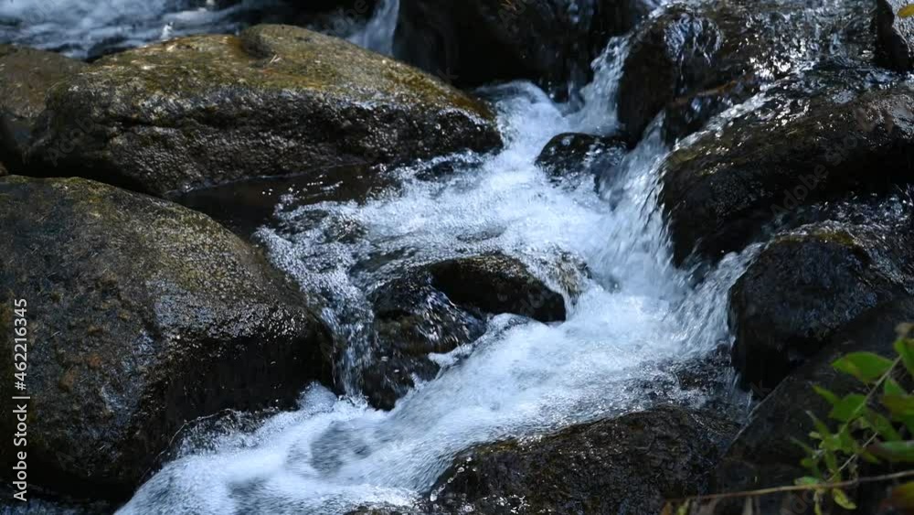 Snowmelt stream running over river rocks on a hike, close up Snowmelt stream running over river rocks on a hike, close up