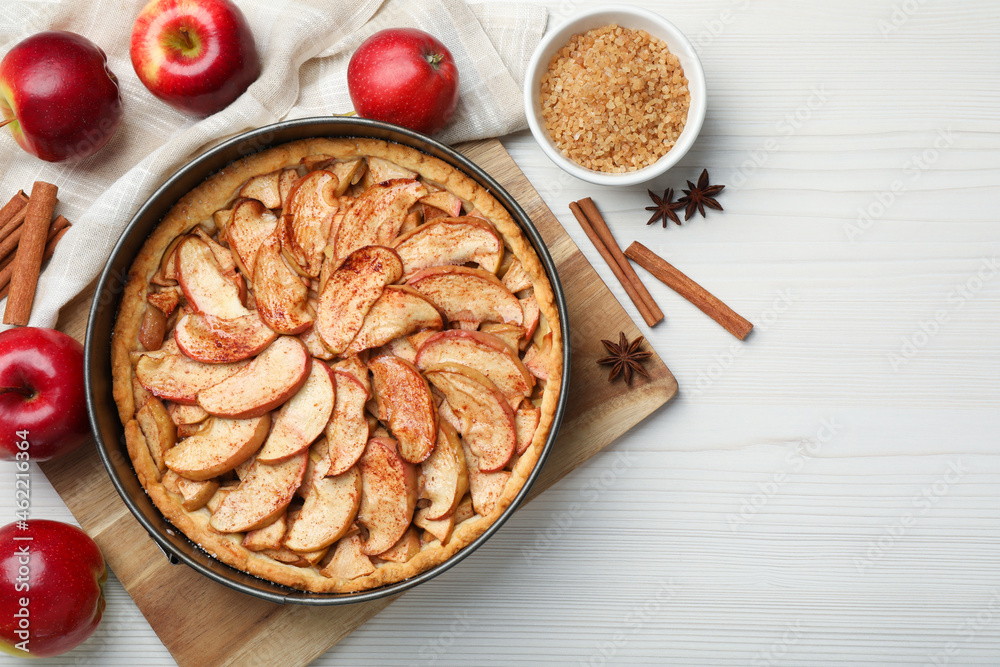 Delicious apple pie and ingredients on white wooden table, flat lay. Space for text - obrazy, fototapety, plakaty 