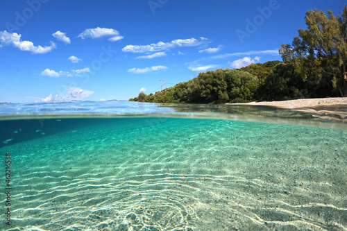 Beautiful underwater split above and below photo of rocky seascape with deep blue sky and clouds and rich marine life in tropical exotic island destination