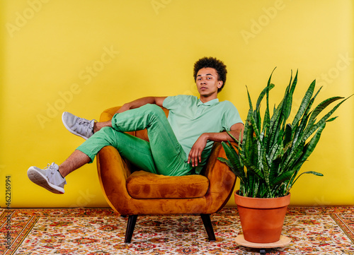 Young man sitting on armchair by plant photo