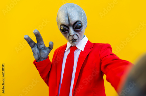Portrait of man wearing alien costume and bright red suit reaching toward camera photo