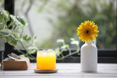 Passion fruit in glass cup and a vase of Yellow gerbera and old book