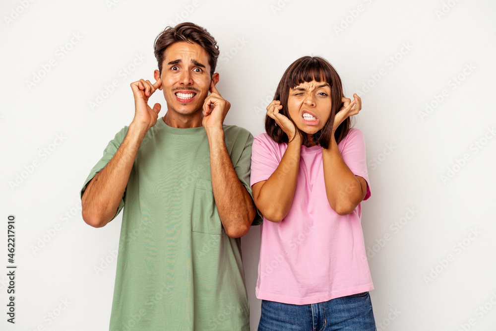 Young mixed race couple isolated on white background covering ears with fingers, stressed and desperate by a loudly ambient. Young mixed race couple isolated on white background covering ears with fingers, stressed and desperate by a loudly ambient.