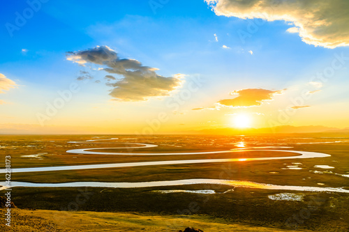 Bayinbuluke Grassland and winding river natural scenery in Xinjiang at sunset,China.The winding river is on the green grassland.