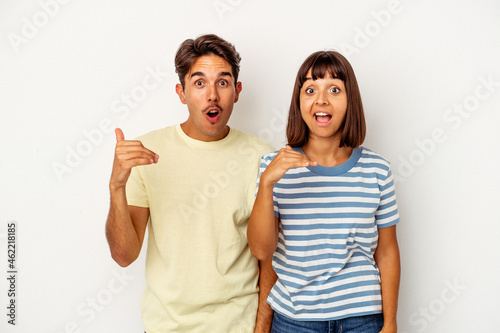 Young mixed race couple isolated on white background laughing about something, covering mouth with hands.
