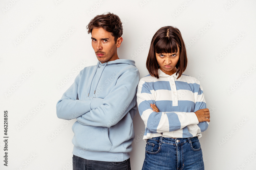 Young mixed race couple isolated on white background frowning face in displeasure, keeps arms folded. Young mixed race couple isolated on white background frowning face in displeasure, keeps arms folded.