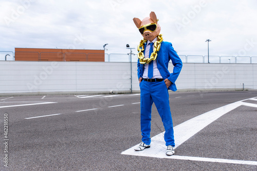 Funny character wearing animal mask and blue business suit having fun on empty parking lot photo