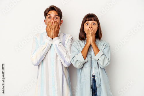 Young mixed race couple isolated on white background shocked, covering mouth with hands, anxious to discover something new. photo