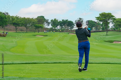 woman Golfer Hitting Ball with Club on Beatuiful Golf Course