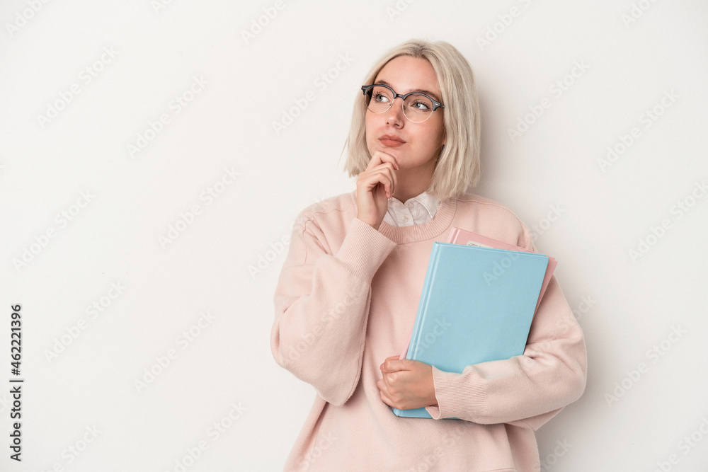Young caucasian student woman holding books isolated on white background looking sideways with doubtful and skeptical expression. Young caucasian student woman holding books isolated on white background looking sideways with doubtful and skeptical expression.