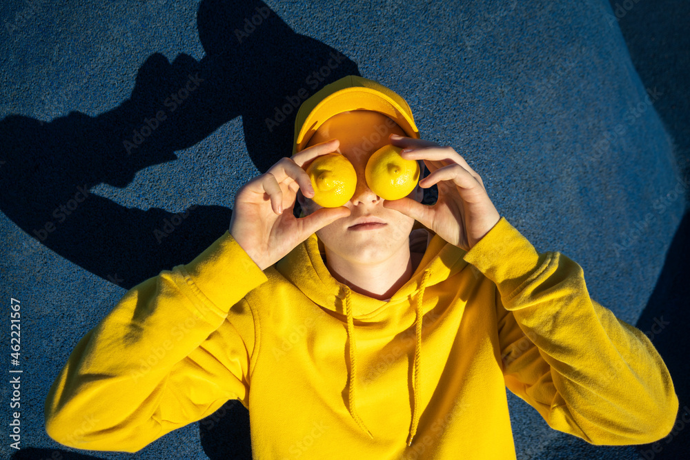 Boy covering eyes with lemons at skateboard park Boy covering eyes with lemons at skateboard park