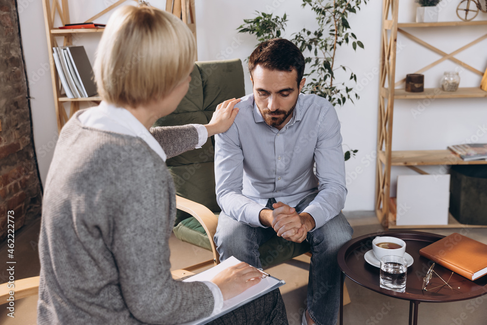 Meeting with psychologist. Young woman, consultant helps sad man cope with depression, despair, problems in life Meeting with psychologist. Young woman, consultant helps sad man cope with depression, despair, problems in life