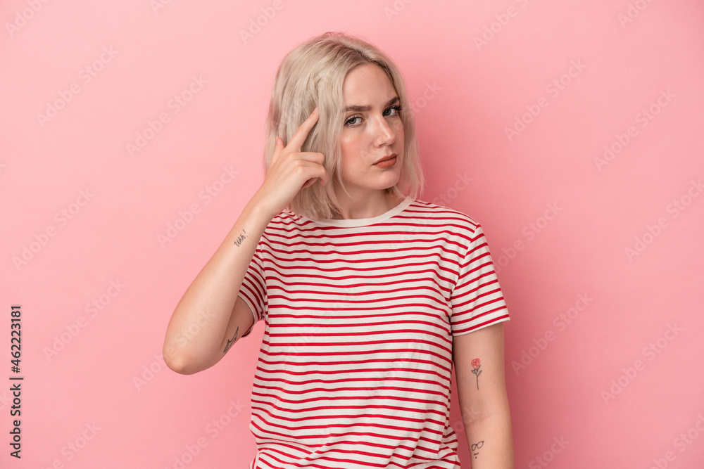 Young caucasian woman isolated on pink background pointing temple with finger, thinking, focused on a task. Young caucasian woman isolated on pink background pointing temple with finger, thinking, focused on a task.