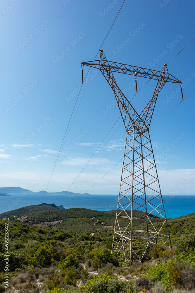 Green landscape of Lefkada island coast in Greece with green woods, blue sky and electrical support line. Vertical