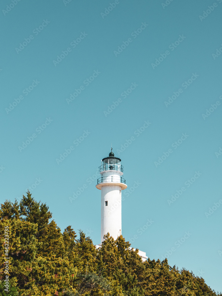 Ionian sea island lighthouse on green cliff on a bright clear blue sky in Greece. Scenic travel destination. Lefkada island. Color graded , vertical