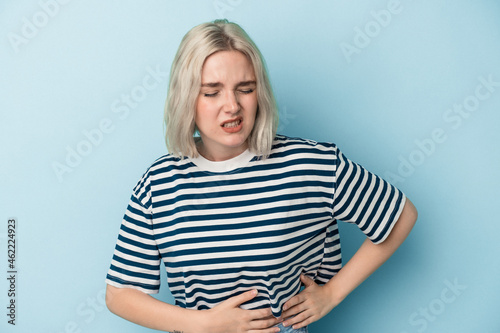 Young caucasian woman isolated on blue background having a liver pain, stomach ache.