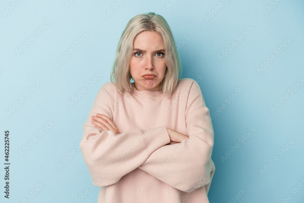 Young caucasian woman isolated on blue background shrugs shoulders and open eyes confused.