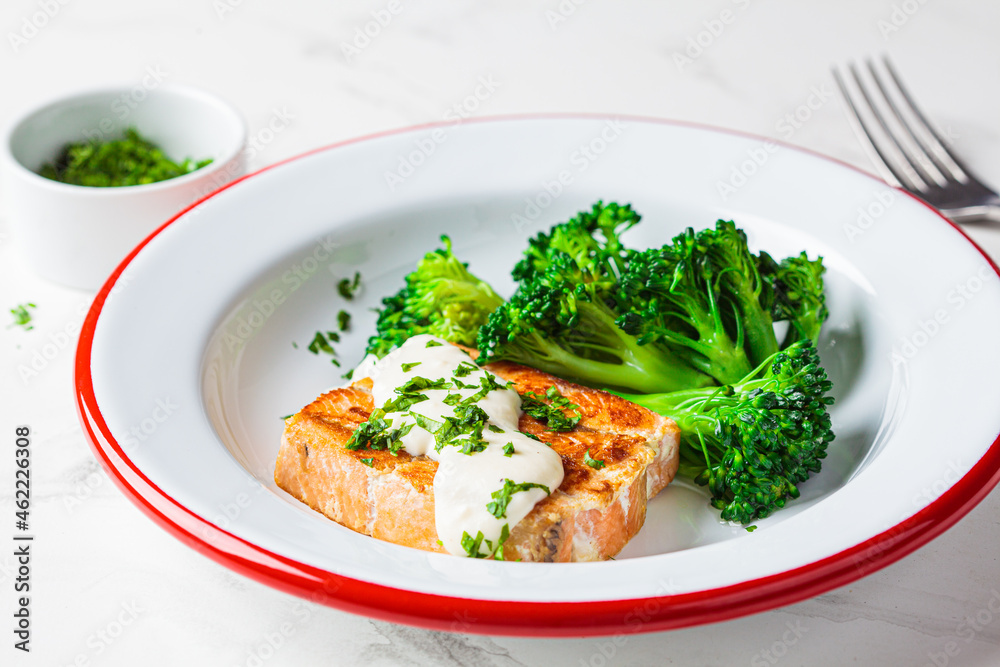 Fried salmon with creamy sauce and broccoli in white plate. Healthy food concept. Fried salmon with creamy sauce and broccoli in white plate. Healthy food concept.
