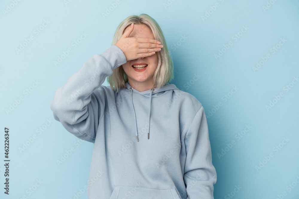 Young caucasian woman isolated on blue background covers eyes with hands, smiles broadly waiting for a surprise. Young caucasian woman isolated on blue background covers eyes with hands, smiles broadly waiting for a surprise.