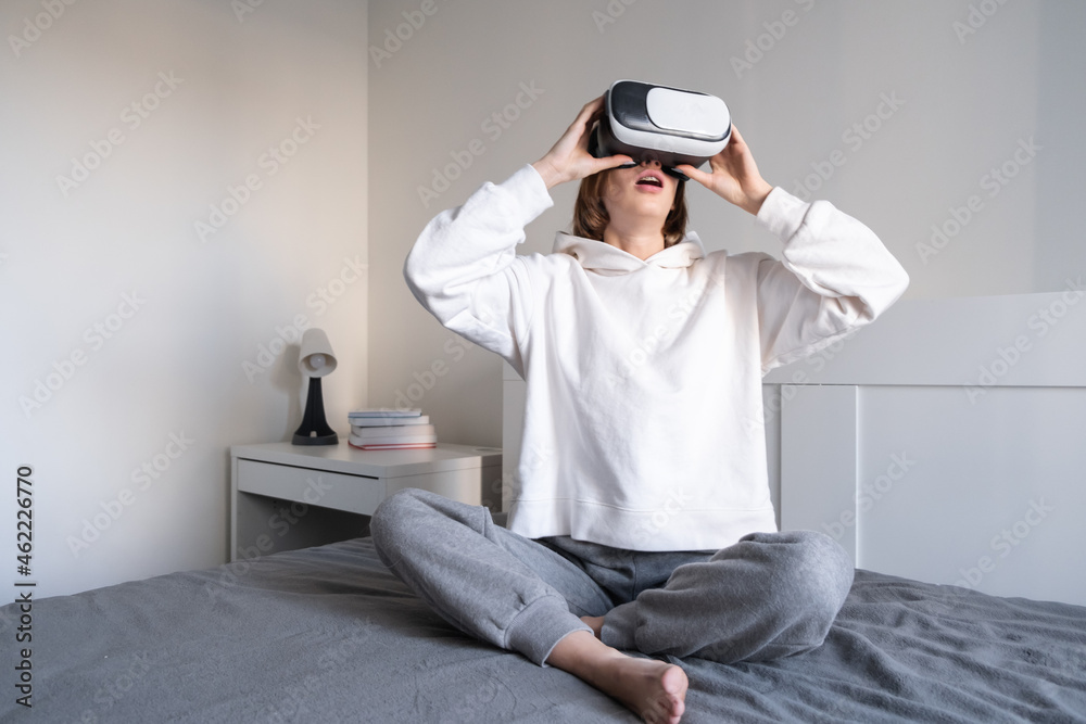 The girl looks into virtual reality glasses at home. A young woman plays virtual games through a special device. The girl looks into virtual reality glasses at home. A young woman plays virtual games through a special device.