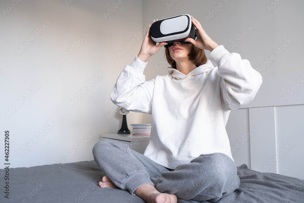 The girl looks into virtual reality glasses at home. A young woman plays virtual games through a special device. The girl looks into virtual reality glasses at home. A young woman plays virtual games through a special device.