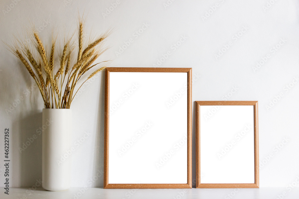 Two wooden frames with organic wheat in a vase with nature light.