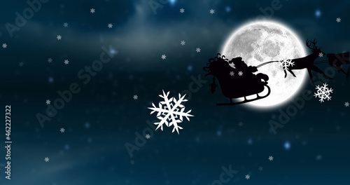 Image of santa claus in sleigh with reindeer at christmas, over snow falling, moon and sky