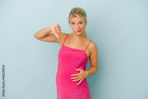Young Russian woman pregnant isolated on blue background showing a dislike gesture, thumbs down. Disagreement concept.