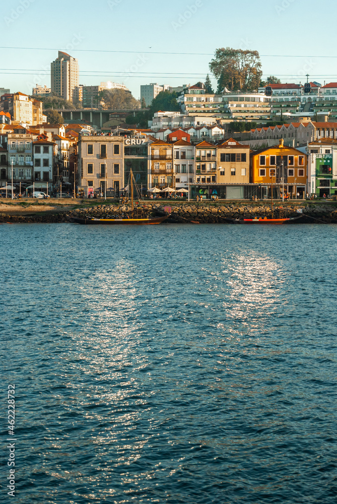Porto, Portugal - September 18, 2021: Colorful embankment of Gaia with wine cellars sun glade reflection on the river Douro waters european style houses