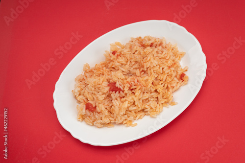 boiled rice with tomato and spices on white dish