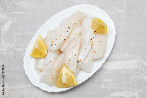 Fototapeta Naklejka Na Ścianę i Meble -  raw squid with pepper and fresh lemon on white dish