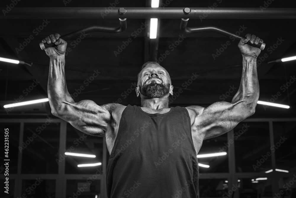 Image of a powerful athlete doing a pullup in the gym. Back pumping