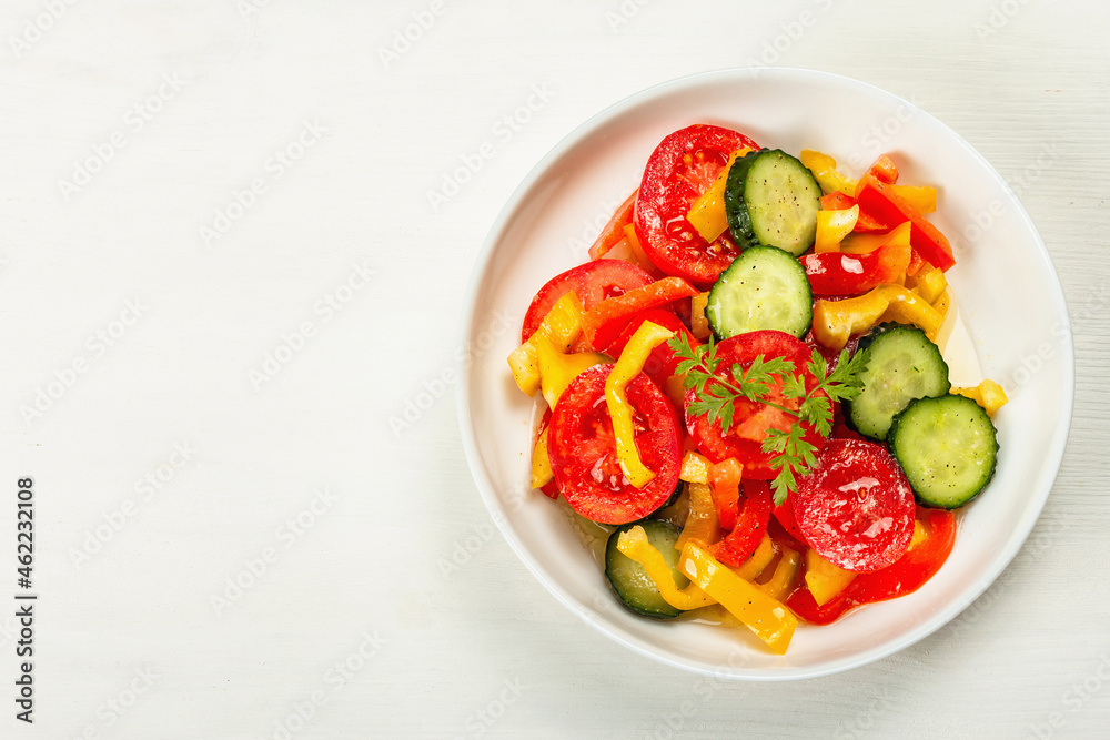 Seasonal fresh vegetable salad with ripe tomatoes, cucumbers, bell peppers