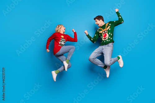 Full length profile photo of hooray young couple jump wear sweater jeans shoes isolated on blue background