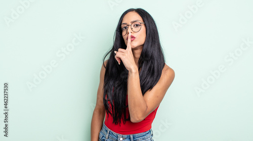 pretty hispanic woman asking for silence and quiet, gesturing with finger in front of mouth, saying shh or keeping a secret photo