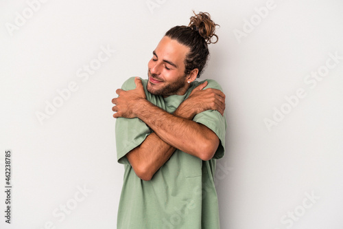 Photography Young caucasian man isolated on gray background hugs, smiling carefree and happy