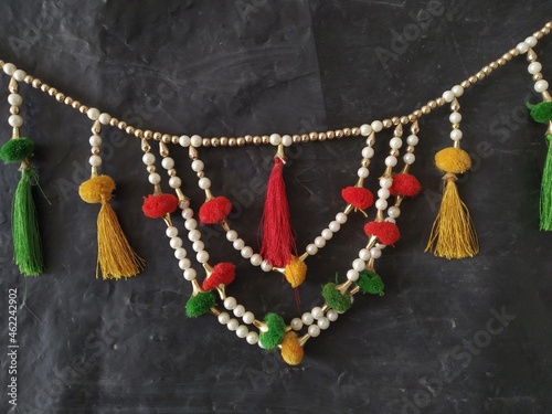 Decoration piece full of colorful threads and golden pearls in a dark background. 