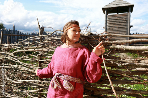 Woman in Scandinavian folk clothes on background of fence