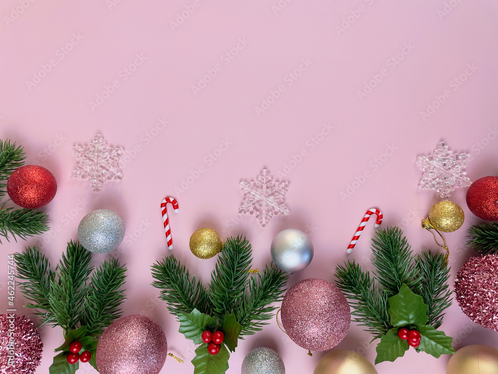 Fototapeta premium Christmas decorations, pine tree leaves, golden balls, snowflakes, red balls on pink background