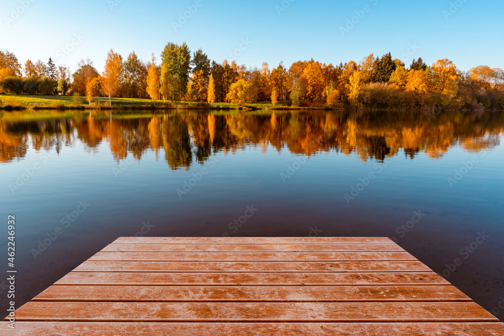 Wooden pier and colorful foliage reflections in lake water
